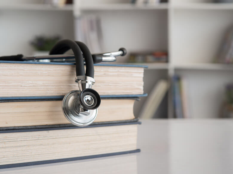 Stacked books with a stethoscope on top.