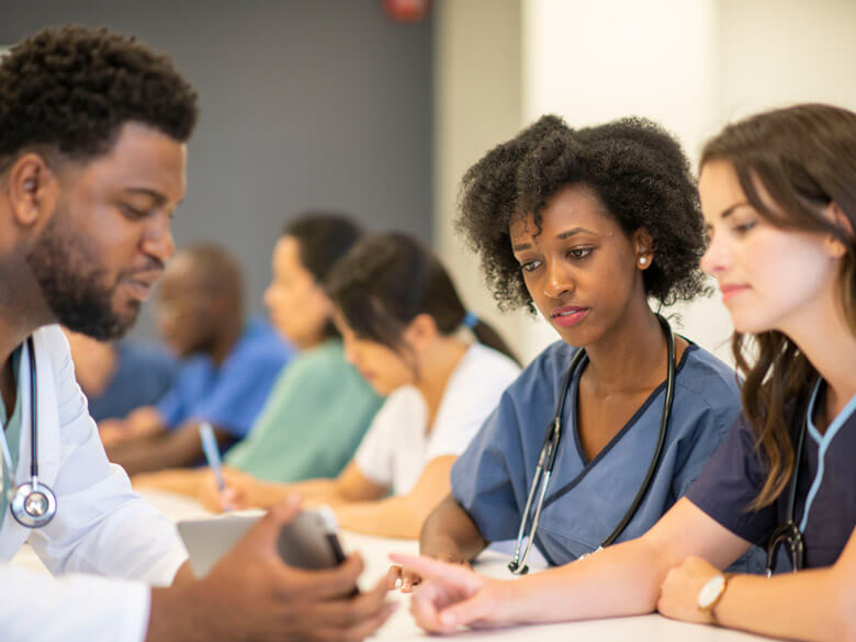 Three doctors in a meeting with a mobile device.