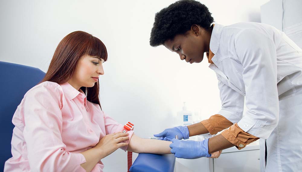 A health care professional prepares to draw blood from a woman's arm.