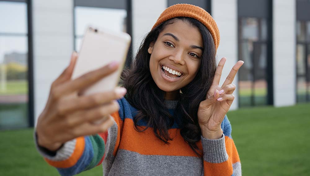 A girl smiles while taking a selfie. 