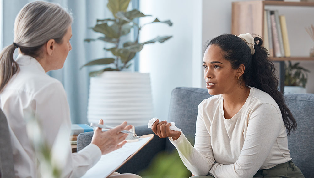 A woman talks with her doctor while holding a tissue in her hand.