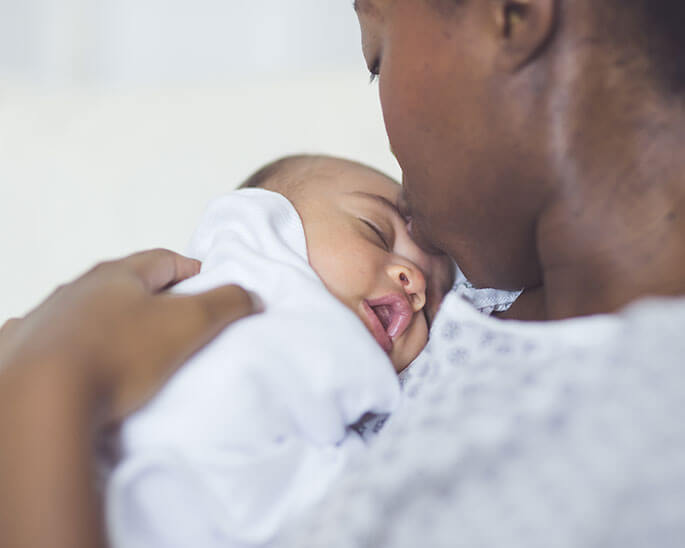 Mother kissing newborn baby on forehead.