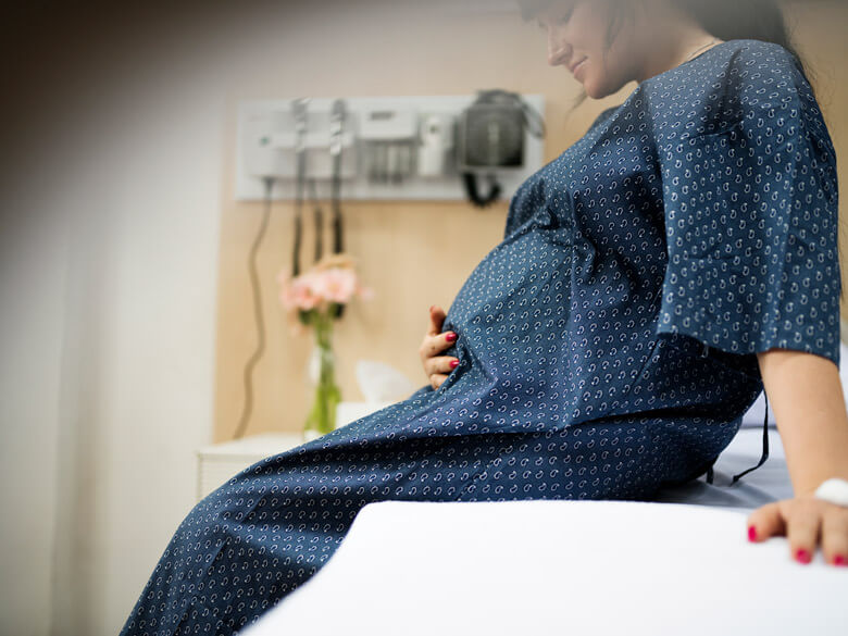 pregnant woman in hospital gown cradling her stomach