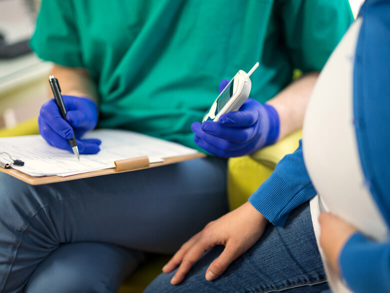 doctor holding a blood sugar test next to pregnant woman