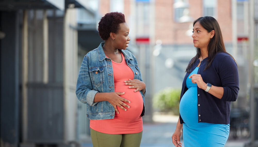 Two pregnant women talking.