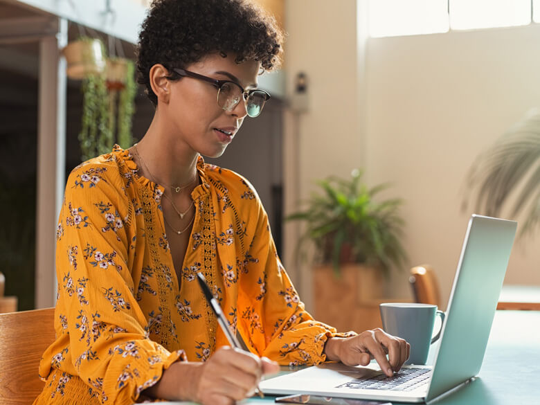 woman in yellow blouse sitting in front of a laptop