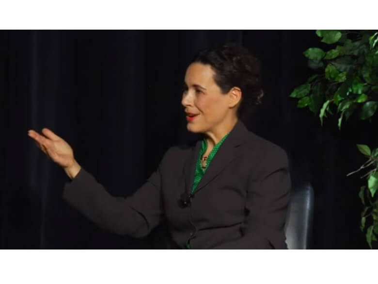 Woman in suit gesturing.