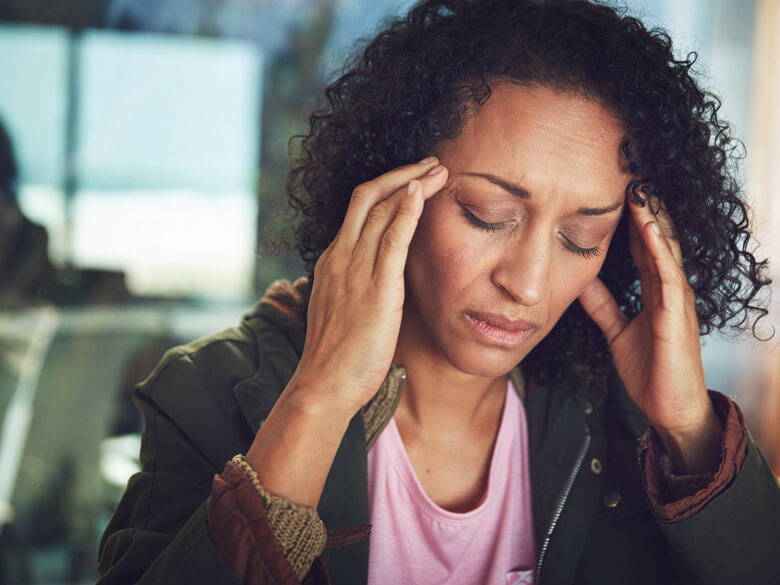 woman frowning and holding her temples as if in pain