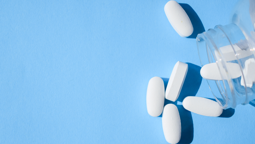 A few oval-shaped white pills scattered on a blue background. 