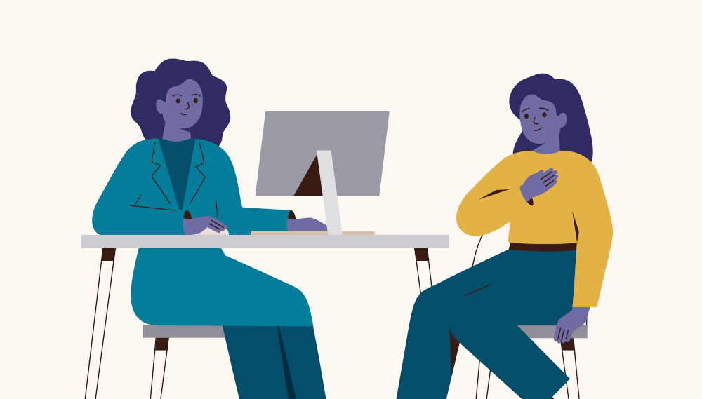 An illustration of two women, a doctor and patient, sitting together at a desk. The patient is smiling and holding her hand on her chest.
